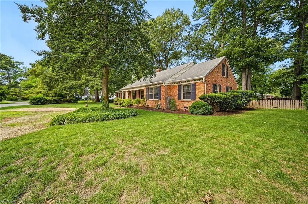 Front lawn, mature trees and brick exterior of the home
